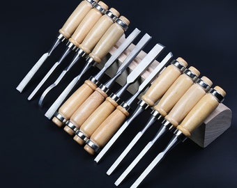 May include: A set of 10 wood carving chisels with wooden handles. The chisels are arranged in a wooden holder. The chisels are made of metal and have different sizes and shapes.