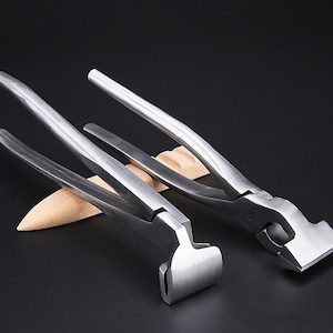May include: Two silver metal pliers with a flat, rectangular jaw. The pliers are on a wooden surface.