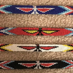 May include: Four beaded headbands with a butterfly design. The headbands are in blue, red, white, and black with colorful geometric patterns.