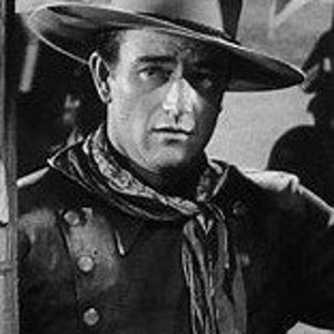 May include: A black and white photo of a man wearing a cowboy hat and a bandana. He is looking off to the side with a serious expression on his face.