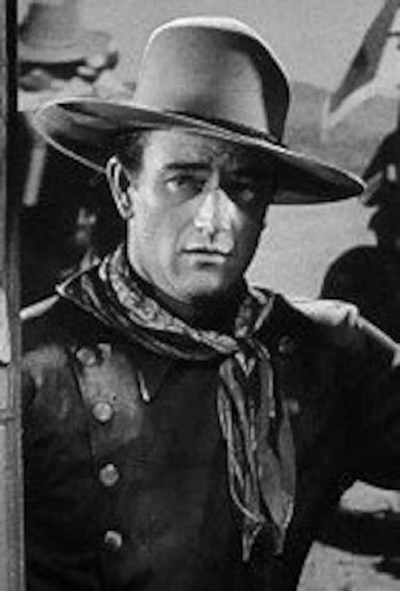 May include: A black and white photo of a man wearing a cowboy hat and a bandana. He is looking off to the side with a serious expression on his face.