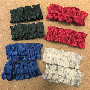 May include: Six pairs of garters in various colors, including green, red, blue, and silver. The garters are made of a soft, stretchy fabric with a ruffled edge.