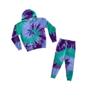 May include: A purple, green and blue tie-dye hoodie and sweatpants set. The hoodie has a drawstring hood and the sweatpants have a drawstring waistband.