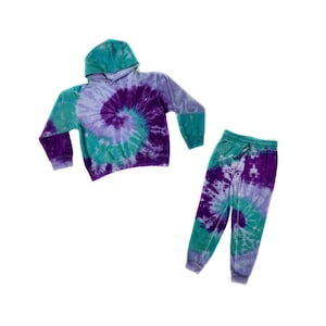 May include: A tie-dye hoodie and sweatpants set in shades of purple, teal, and light blue. The set features a swirling tie-dye pattern.