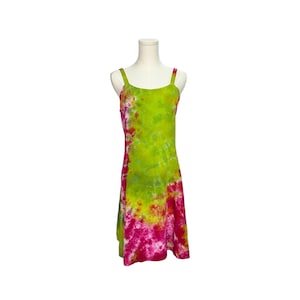 May include: A sleeveless knee-length dress featuring a vibrant tie-dye pattern in shades of lime green, bright yellow, and magenta pink. The garment has a scoop neckline and wide shoulder straps, displayed on a white mannequin torso.