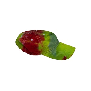 May include: A baseball cap featuring a vibrant tie-dye pattern in shades of bright red, lime green, and yellow. The cap has a curved brim, white stitching details, and small white eyelets on the crown, showcasing a colorful, blended fabric design.
