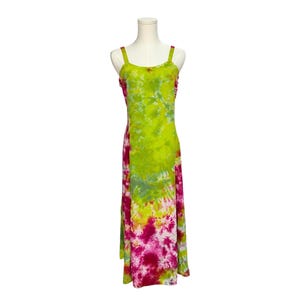 May include: A sleeveless maxi dress featuring a vibrant tie-dye pattern in shades of lime green, magenta, and white. The garment has a scoop neckline, wide shoulder straps, and a floor-length silhouette that flows straight down from the bodice.