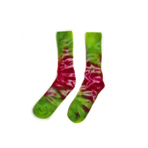 May include: A pair of crew-length socks featuring a vibrant tie-dye pattern in shades of lime green and deep magenta. The socks have a ribbed cuff at the top and a rounded toe, with the colorful dye swirling across the fabric in a marbled effect.