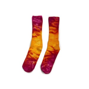 May include: A pair of tie-dye socks in shades of pink, orange, and yellow. The socks are made of a soft, comfortable material and have a crew length.