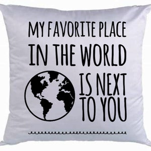 May include: White throw pillow with black text that reads "My favorite place in the world is next to you". A black and white illustration of the world is next to the text.