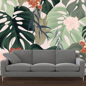 Pode incluir: Um sofá cinza em frente a uma parede com um papel de parede de estampa tropical com grandes folhas verdes, flores rosa e vermelhas e um fundo branco.