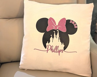 Puede incluir: Una almohada blanca con una silueta de Mickey Mouse negra y rosa, un lazo rosa y un castillo. El texto "Phillips" y "2025" también están en la almohada.