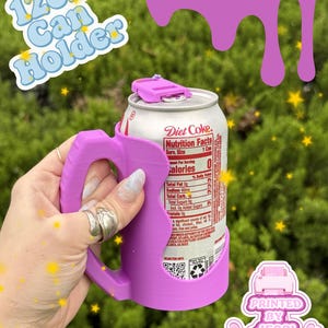 May include: A magenta 12oz can holder with a handle, designed to fit a standard beverage can. The holder features a top tab and a side handle for gripping. Text on the image includes 12oz Can Holder, magenta, and Printed By Jessi.