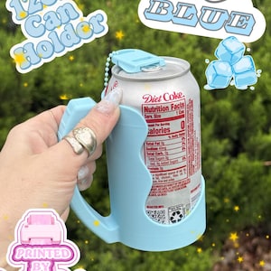 May include: A light blue plastic 12oz can holder with a handle and a top tab, holding a silver Diet Coke aluminum can. The holder features a small ball chain attachment. Text on the image includes 12oz Can Holder, ice BLUE, and PRINTED BY JESSI.