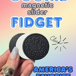 May include: A cookie-shaped magnetic slider fidget toy with a black textured exterior and a white center layer. The text COOKIE magnetic slider FIDGET and AMERICA'S FAVORITE FIDGET appear in blue, along with the word Click! and a starburst graphic.