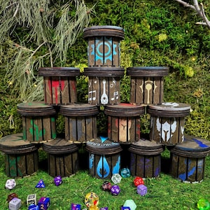 May include: A collection of wooden dice boxes with various painted symbols and designs, including musical notes, gears, and flames. The boxes are arranged on a bed of green moss, surrounded by colorful dice.