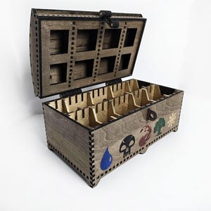 May include: Wooden box with a hinged lid and compartments for storing cards. The box is decorated with five symbols representing the elements of earth, fire, water, air, and spirit.