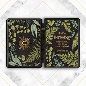 Pode incluir: Capa preta para iPad com design de livro vintage. A capa está aberta, revelando o interior e a lombada. O lado esquerdo apresenta um desenho de sol dourado e ilustrações botânicas. O lado direito diz "Book of Herbology" com texto sobre plantas e ervas mágicas.