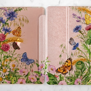 Könnte beinhalten: Eine rosa und weiße Blumen-iPad-Hülle mit einem Aquarell-Design aus Schmetterlingen, Wildblumen und Weizenähren.