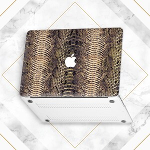May include: A white laptop computer with a snakeskin pattern on the lid. The Apple logo is visible on the lid.