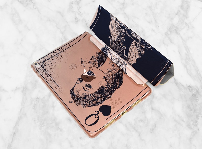 Może przedstawiać: Etui na iPada w kolorze r&oacute;żowego złota z czarno-białym rysunkiem twarzy kobiety z kwiatowymi detalami. Etui ma czarny symbol pika i napis "Queen of Hearts".