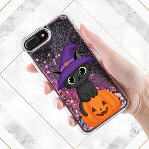 May include: A clear phone case with a black cat wearing a purple witch hat and sitting on a pumpkin. The case is filled with pink and silver glitter.