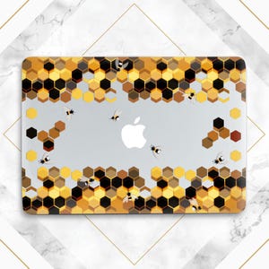 Könnte beinhalten: Eine Laptop-Hülle mit einem Bienenwabenmuster in Gelb-, Braun- und Schwarztönen. Das Design umfasst mehrere Cartoon-Bienen. Das Apple-Logo ist sichtbar.