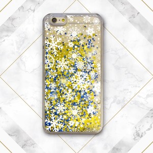 May include: A clear phone case with a glittery design featuring white snowflakes and blue and gold stars.