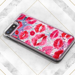 May include: A clear phone case with a glittery pink and white background and red lips printed on it.