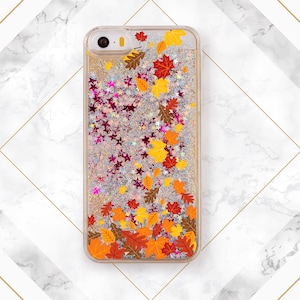 May include: A clear phone case with a glittery background and a design of autumn leaves in shades of orange, yellow, and red.