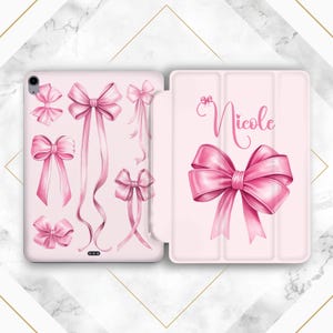 May include: A pink iPad case featuring a pink bow design and the name "Nicole" printed on the front.