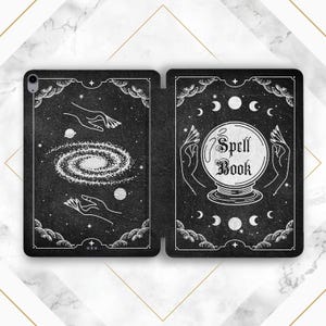 Peut inclure: Illustration en noir et blanc d'un grimoire avec une boule de cristal, des étoiles et des lunes sur un fond noir. Le texte "Spell Book" est écrit en police gothique.