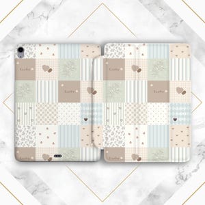 May include: A pastel-colored tablet case with a patchwork design. The case features squares with floral, heart, and polka dot patterns. The word "Lucky" is printed on several squares. The case is open, revealing the tablet screen.