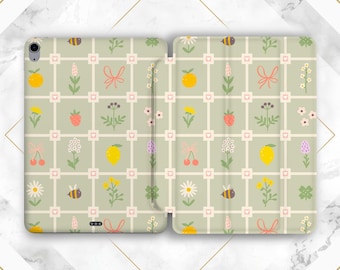 May include: An open tablet case with a light green background featuring a grid pattern. The pattern includes illustrations of fruits, flowers, bees, and bows in various colors. The case is designed to protect the tablet.