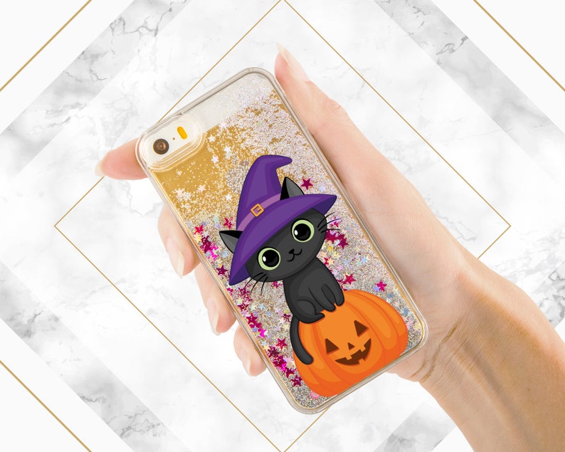 May include: A gold glitter phone case with a black cat wearing a purple witch hat and sitting on a jack-o'-lantern.