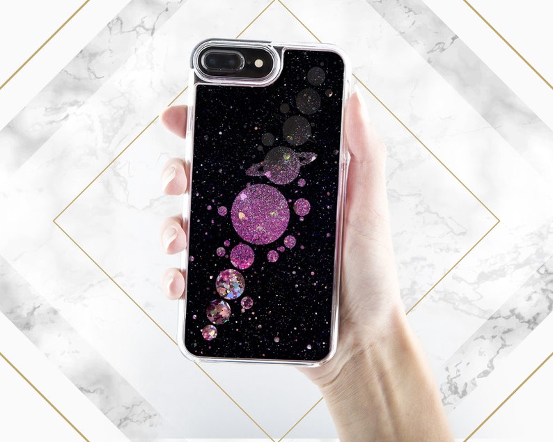 May include: A black phone case with a glittery design featuring pink and gold circles and a galaxy-like background.