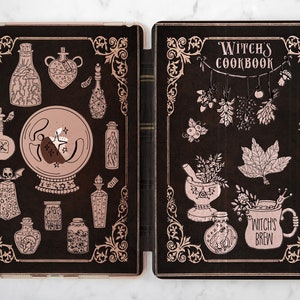 May include: A black and rose gold iPad case with a witchy theme. The front cover features a crystal ball, potion bottles, and a skull. The back cover features a mortar and pestle, a cauldron, and the text "Witch's Cookbook".