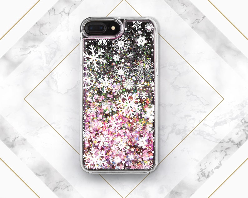 May include: A clear phone case with a glittery pink and white snowflake design. The case is designed for an iPhone.