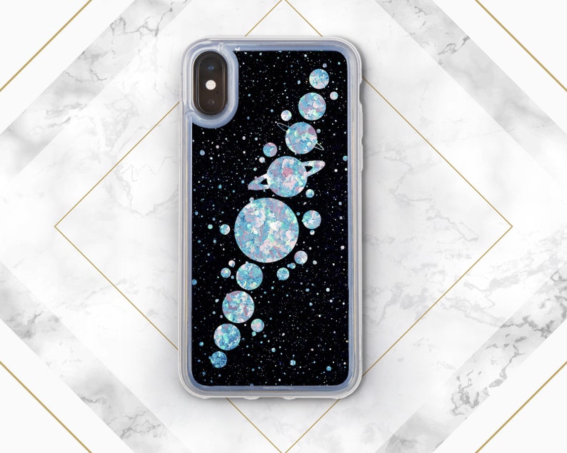 May include: A black phone case with a glitter background and a design of planets and stars. The planets are iridescent and have a sparkly finish.