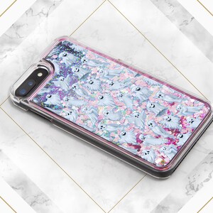 Puede incluir: Una funda transparente para tel&eacute;fono con un dise&ntilde;o de purpurina rosa y blanca con un patr&oacute;n de fantasmas. La funda est&aacute; dise&ntilde;ada para un iPhone.