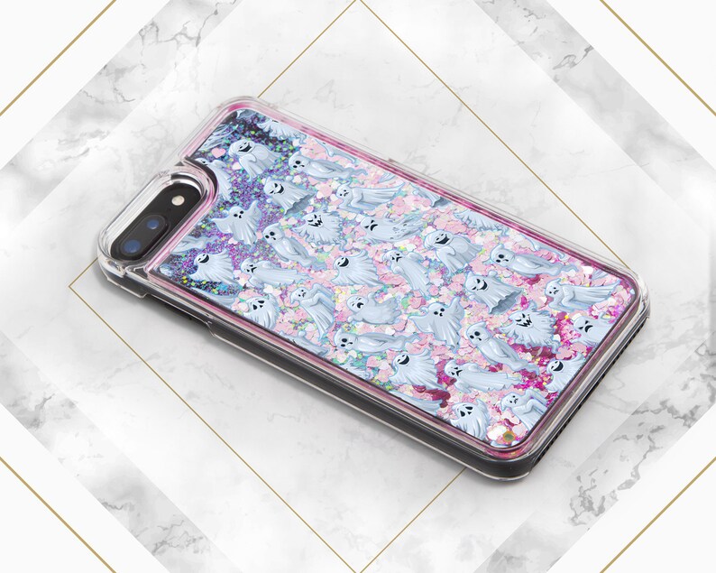 Puede incluir: Una funda transparente para tel&eacute;fono con un dise&ntilde;o de purpurina rosa y blanca con un patr&oacute;n de fantasmas. La funda est&aacute; dise&ntilde;ada para un iPhone.