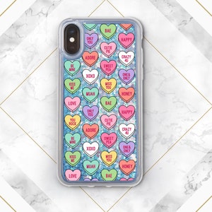Może przedstawiać: Przezroczyste etui na telefon z błyszczącym niebieskim tłem i kolorowymi naklejkami w kształcie serca z r&oacute;żnymi romantycznymi napisami. Etui ma przezroczyste plecy i czarną ramkę.