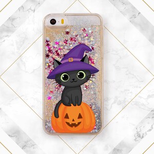 May include: A clear phone case with a glittery background and a black cat wearing a purple witch hat sitting on a jack-o-lantern.