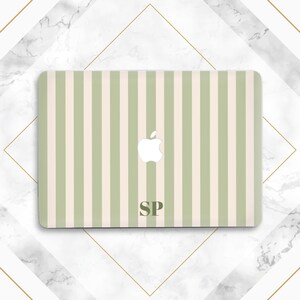 Op de afbeelding: Een laptopskin met een verticaal streeppatroon in afwisselend saliegroen en crème. In het midden staat een wit Apple-logo en onderaan in het midden staan de donkergroene hoofdletters SP in een schreeflettertype.