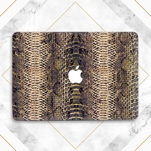 May include: A laptop computer with a gold and brown snakeskin pattern skin. The Apple logo is visible on the front of the laptop.