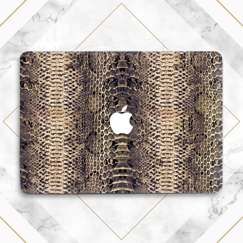 May include: A laptop computer with a gold and brown snakeskin pattern skin. The Apple logo is visible on the front of the laptop.
