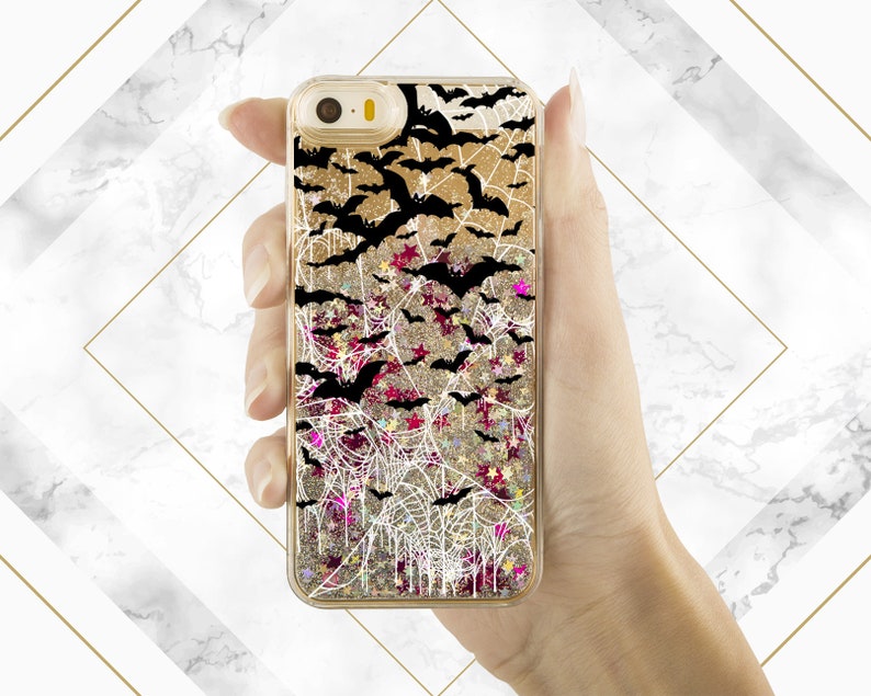 May include: A gold glitter phone case with a black and white spiderweb design and black bats. The case has a clear back and a glittery liquid inside.