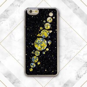May include: A black phone case with a glitter design of a solar system. The planets are yellow and blue with glitter accents. The background is black with a subtle glitter effect.