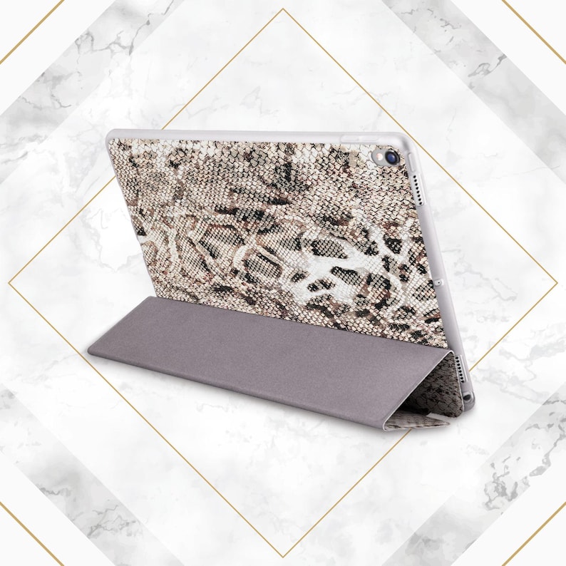 May include: A gray and brown snakeskin patterned tablet case with a stand feature. The case is folded to show the stand feature.