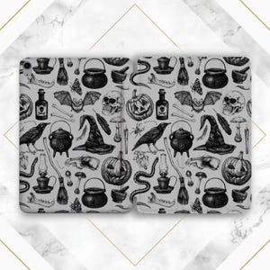 May include: A gray phone case featuring a repeating pattern of Halloween-themed illustrations. The design includes witch hats, skulls, pumpkins, potion bottles, crows, cauldrons, and other spooky elements. The case is open, revealing the interior.